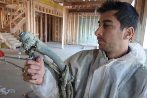 George Shimi holds spray foam gun inside new Toronto home insulation
