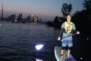 Niv is paddlebaording at night in Toronto